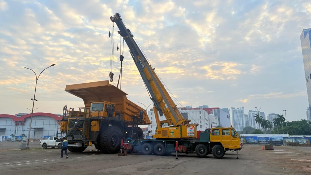 Mobile crane mengangkat bucket heavy dump truck di kawasan industri Marunda